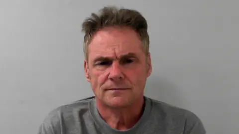 Mugshot of Darren Harris, with grey/brown hair and wearing a grey sweatshirt.