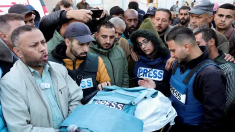 Reuters Journalists and other Palestinian mourn next the body of Al Jazeera cameraman Ahmad Baker al-Louh, after he was killed in an Israeli air strike in Nuseirat refugee camp, central Gaza (16 December 2024)