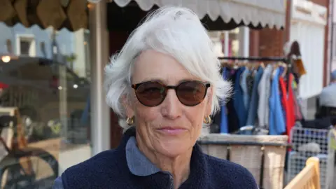 John Fairhall/BBC A head and shoulders image of a woman wearing a navy fleece and sunglasses. She is smiling and looking into the camera.