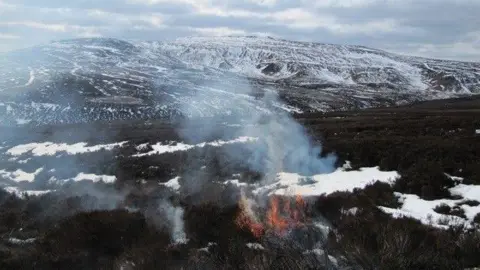 Geoff Eyre A snowy moorland with a small fire in the foreground.
