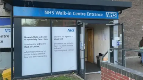 The entrance to Norwich's NHS walk-in centre. There is an automatic door and a large window to the left.