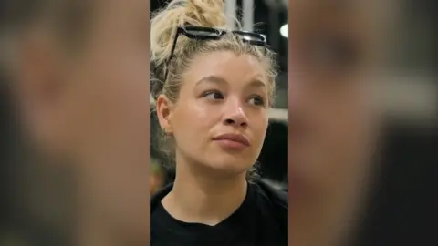 Molly looks unimpressed - she has blonde hair tied up and glasses on top of her head