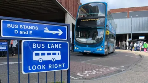 Andrew Turner/BBC Bus exiting Great Yarmouth bus station with signs in the foreground