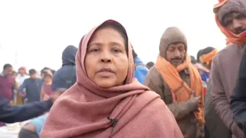 A devotee wears a scarf around her head and speaks to the press after escaping the crush at India's Kumbh Mela. 