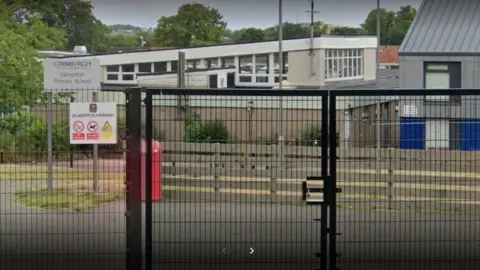 Google A big black gate with school buildings behind.