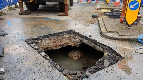 Thames Water Large hole in road, filled with water. 