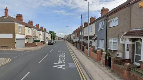 A Google Street View of Alexandra Road in Grimsby. It shows a road with residential houses on both sides.