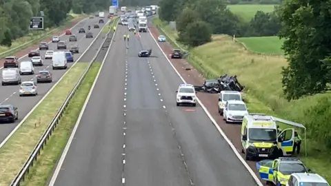 A view of a section of the M6 taken from a bridge showing the accident scene, with emergency vehicles on the hard shoulder