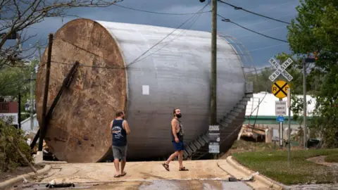 Getty Images Men survey the destruction from Helene in Asheville, North Carolina