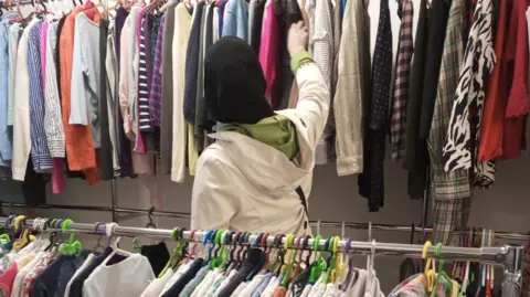 The Free Shop Racks of clothes and a woman looking through them