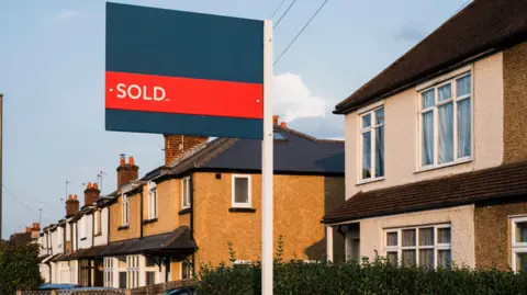 A sold sign outside a row of semi-detached houses