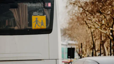 Getty Images A stock image showing the back of a white coach with a yellow school bus icon fixed to the window.