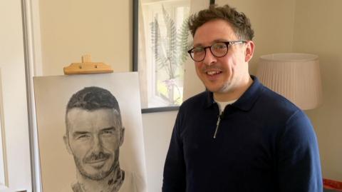 Del LLewllyn sitting next to his drawing of David Beckham