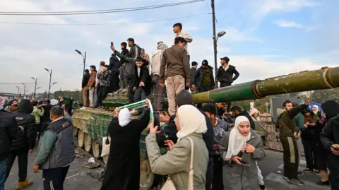 Getty Images People celebrate at Umayyad Square in Damascus on December 8, 2024. 