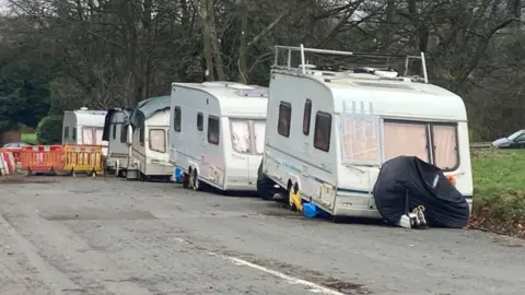 A line of five caravans, all of them white, parked on The Downs in Bristol