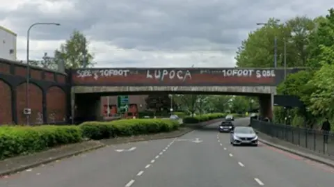 General view of a dual carriageway on Icknield Street, Hockley, Birmingham. A bridge with graffit on it is visible