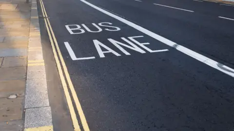 Getty Images a road with white bus lane markings, the words bus lane are visible in capital letters in the middle of the lane