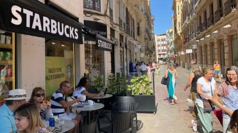 Guy Hedgecoe Orang-orang duduk di luar Starbucks di Málaga sambil minum kopi