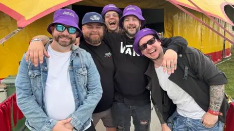 The five members of Manor Heights wearing purple BBC Radio Shropshire hats at Camp Bestival