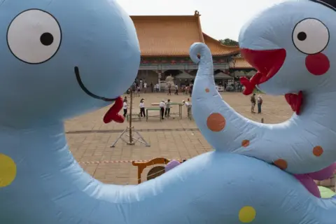 KIM LUDBROOK / EPA Inflatable blue snakes with friendly, cartoonish faces stand in front of a tradional-looking Chinese building.