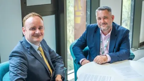 Local Democracy Reporting Service Adam Brown with short brown hair and Jason Smithers with dark hair and beard sitting at a table