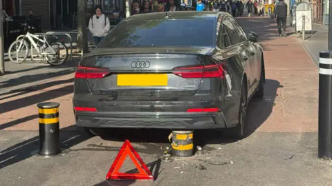 A car with a rising bollard touching its underside. 