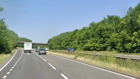 Google A dashcam picture of one side of the A45, taken in summer. There are two lanes. The traffic is light, but there is a van and two cars ahead.