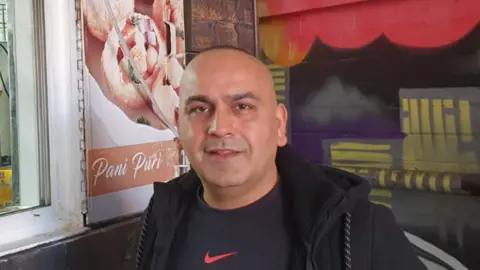 BBC Man beside food poster 