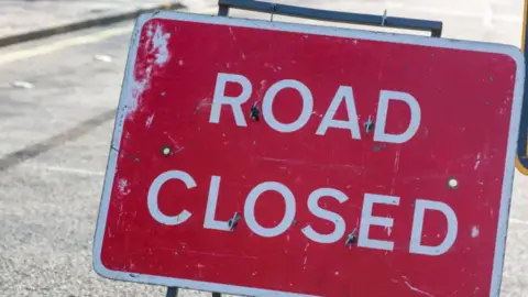 A red Road Closed sign on a street