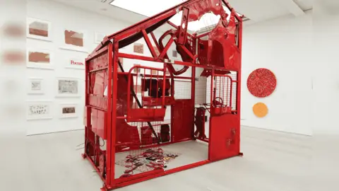 Homewards The red sculpture made from a Peugeot 206 car