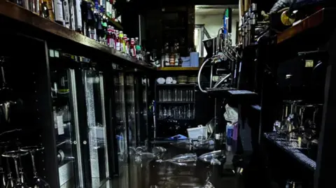 Floodwater can be seen pooling behind the bar in the The Woolpack.