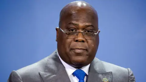 The president of Dr. Félix Tshisekedi is wearing a bright gray suit and a blue tie.