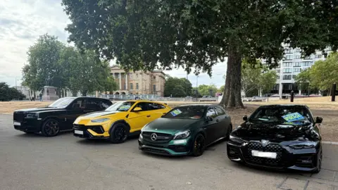Met Police A Black Rolls-Royce, yellow Lamborghini, green Mercedes and black BMW parked side by side after being seized