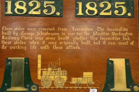 Henry Aldridge and Son Ltd/PA Wire The nameplates are displayed on a decorative wooden board. The numbers on the plates are gold in colour and stand on a green background.