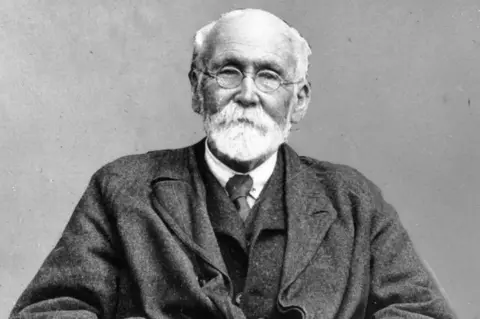 Getty Images A black and white photo of Joseph Rowntree, who has white facial hair and short white hair. He is wearing rounded glasses.