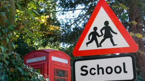 School crossing sign, telephone box in background - stock photo