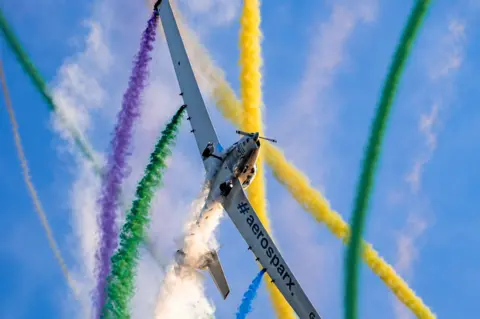 Visit Great Yarmouth A plan with aerosparx branding on its wings can be seen as colourful smoke billows out of it on a blue, sunny day