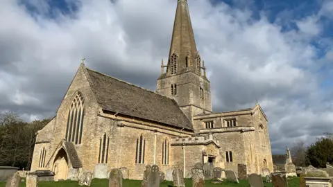 St Mary's church. It is a large pale stone building with a large nave and bell tower. It is surrounded by a graveyard.