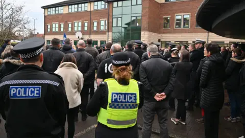 North Yorkshire Police A crowd of police officers stand with hands behind their backs at a vigil outside North Yorkshire Police HQ.