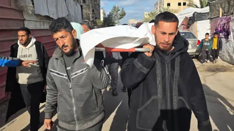 Mourners carry the body of a Palestinian who was reportedly killed in an Israeli air strike, at Nasser hospital, in Khan Younis, southern Gaza (4 February 2026)