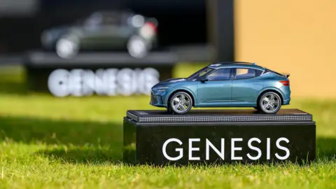 PA Media Close up of a small green model car on top of a black base which has Genesis written on it