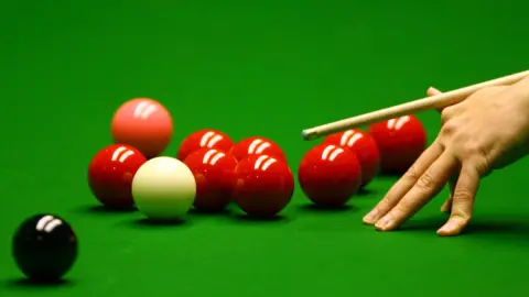 Getty Images A hand holding a snooker cue, preparing to play a shot