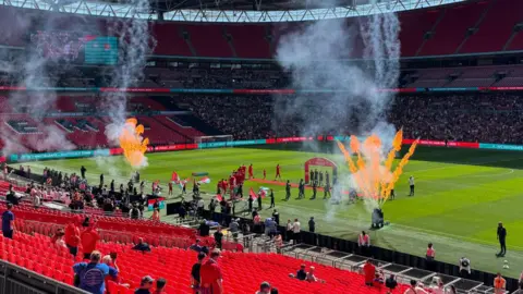 BBC A football stadium with flares going off.