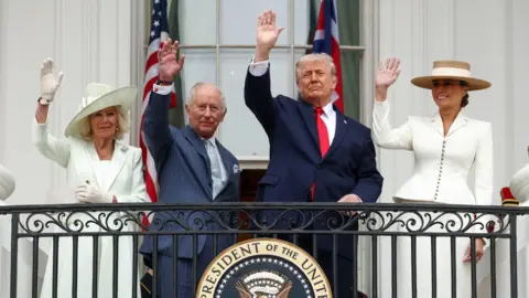 The Queen, King, Donald and Melania Trump all wave in formal attire with a plaque that says 'Seal of the president of the United States' as they stand on the balcony of the White House on Tuesday.