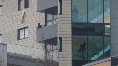 BBC/Oli Constable Armed police standing on a balcony in the picture on the left and climbing stairs inside the building on Broad Street in the right hand picture.