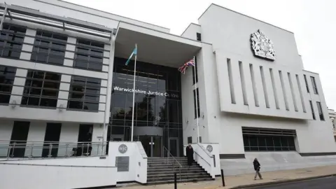 A google street view image of the outside of a court. a large white building with glass frontage and bars on the windows