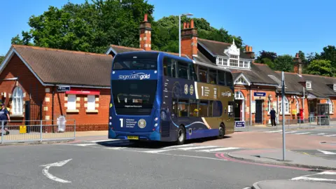 Network Rail A blue and gold double decker bus outside Farnborough rail station