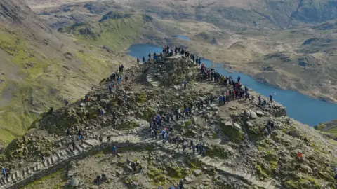 BBC/Cwmni Da Hikers queuing on the summit of Yr Wyddfa