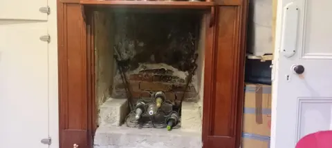 Supplied: Jo Hartmann A fireplace with a rack of wine bottles in the middle