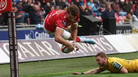 Taine Plumtree dives acrobatically to score Scarlets' first try against Dragons